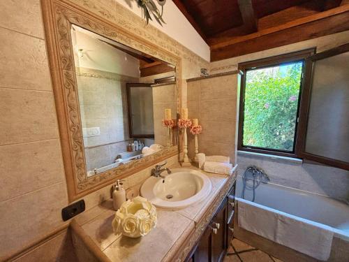 W łazience znajduje się umywalka, wanna i lustro. w obiekcie La casetta holiday w mieście Fiumicino
