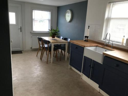 a kitchen with blue cabinets and a table with chairs at Caerlaverock Cottage in Prestwick