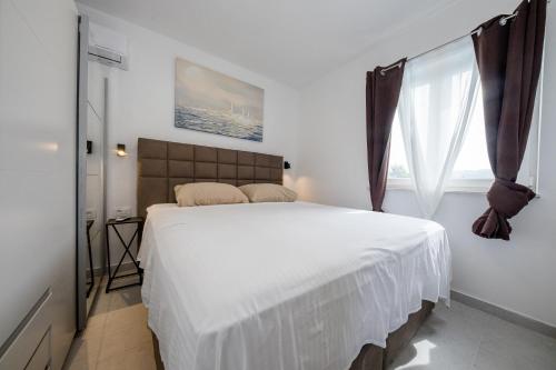a bedroom with a large white bed with a window at Villa Silente in Supetarska Draga