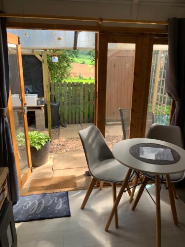 - Sala de estar con mesa y sillas y patio en Hedgehog Lodge en Colwall