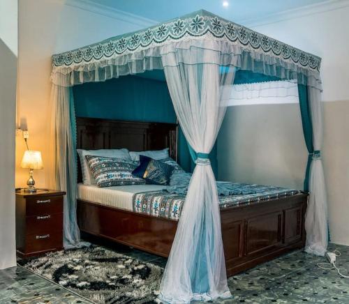 - une chambre avec un lit à baldaquin bleu dans l'établissement GE-Homes, à Dar es Salaam