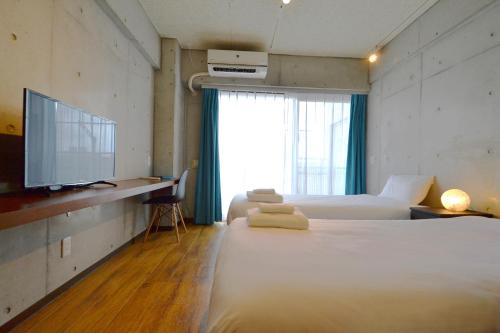 una camera d'albergo con letto e TV di Hotel Pescatore Okinawa a Naha
