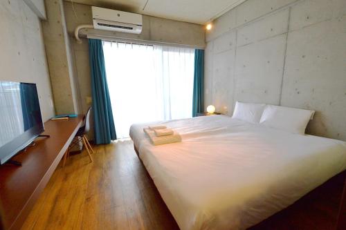 a bedroom with a large white bed and a television at Hotel Pescatore Okinawa in Naha