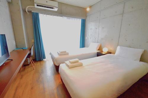 那霸的住宿－Hotel Pescatore Okinawa，酒店客房设有两张床和电视。