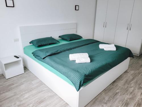 uma cama branca com lençóis verdes e toalhas em Cosy apartment Fagaras em Făgăraş