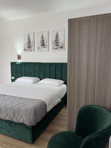 a bedroom with a bed with a green headboard and a chair at Hotel Floga in Shkodër