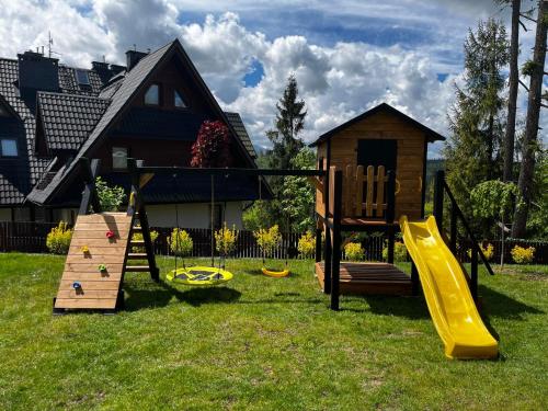 a yard with a playground with a slide and a house at Willa Koszysta in Bukowina Tatrzańska