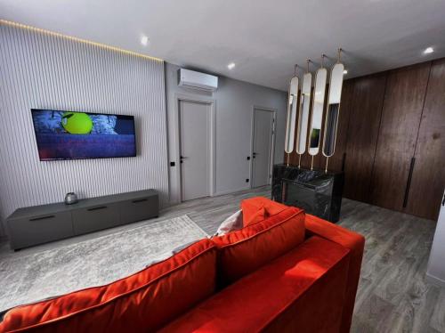 un soggiorno con un divano rosso e una TV di Royal Lux апартаменты в ЖК ZAMAN a Atyraū