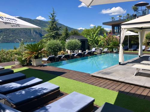 een zwembad in een hotel met stoelen en een parasol bij Les Suites du Lac in Aix-les-Bains