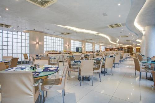 a dining room with tables and chairs and windows at Hotel Le Palme - Premier Resort in Milano Marittima