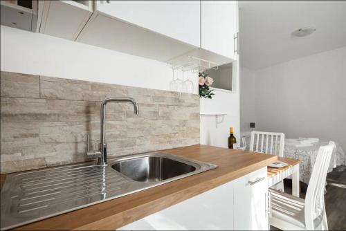 a kitchen with a stainless steel sink and white cabinets at La Casa di Luna in Riomaggiore