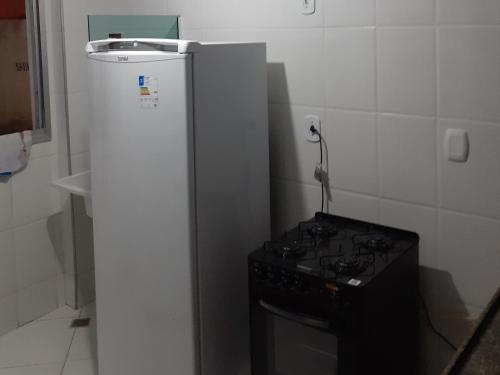 a small kitchen with a stove and a refrigerator at Apartamento 101 com vista da piscina e mar in Piúma
