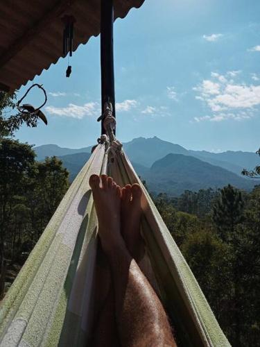a person lying in a hammock looking out at the mountains at Cabana nas montanhas! in Resende