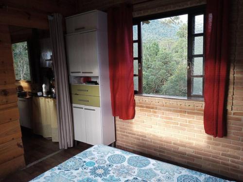 a kitchen with a window and a brick wall at Cabana nas montanhas! in Resende
