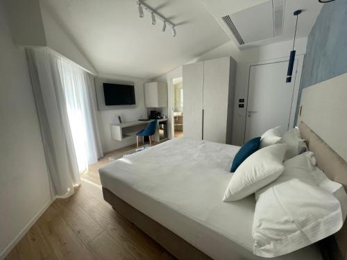 - une chambre avec un grand lit blanc et un bureau dans l'établissement Chic & Charme Luxury Rooms, à Olbia