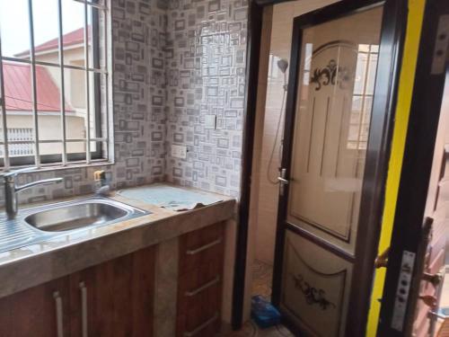 uma cozinha a ser remodelada com um lavatório e uma janela em Abokobi Cosy Home em Accra
