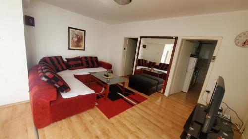 ein Wohnzimmer mit einem roten Sofa und einem TV in der Unterkunft Aleks 4 in Skopje