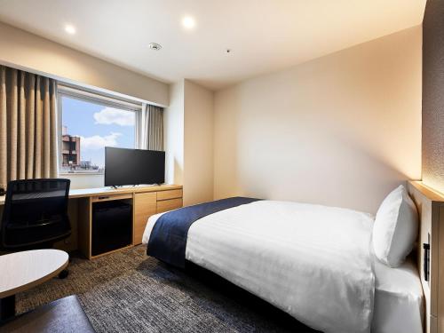a hotel room with a bed and a flat screen tv at Daiwa Roynet Hotel Gifu in Gifu