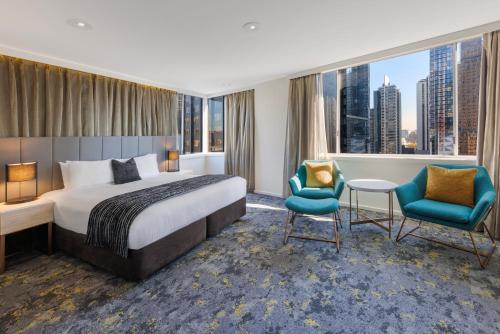 a hotel room with a bed and two chairs at Hotel Grand Chancellor Melbourne in Melbourne