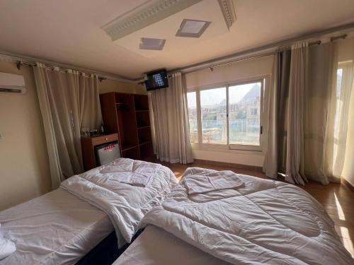 1 Schlafzimmer mit 2 Betten und einem großen Fenster in der Unterkunft Sphinx and Pyramids INN in Kairo