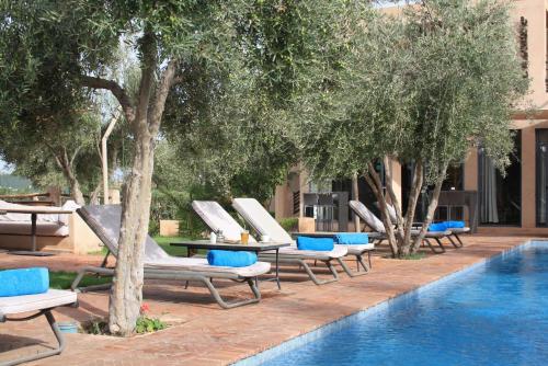 a row of lounge chairs next to a swimming pool at Villa Katia in El Harkat