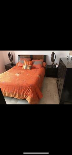 a bed with orange sheets and pillows in a bedroom at villa amplia y acogedora-alcudia smir in Fnidek