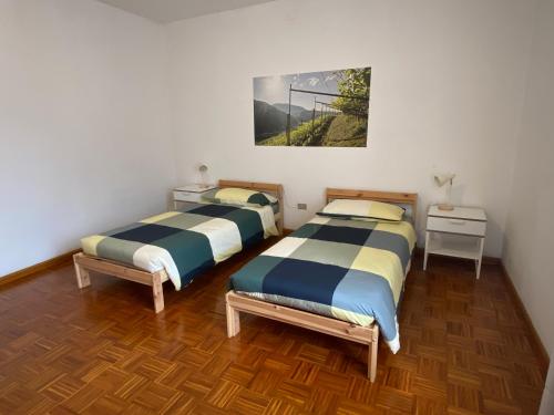 two beds in a room with a painting on the wall at Casa alla Fontana in Serravalle allʼAdige