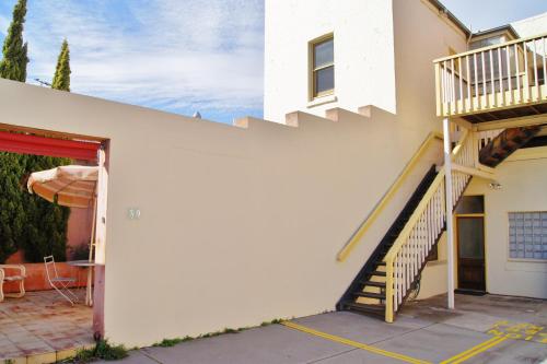 a white house with a staircase and a patio at Fire Station Inn in Adelaide