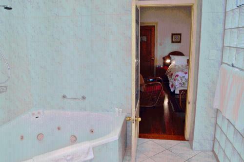 a bathroom with a bath tub and a bedroom at Fire Station Inn in Adelaide