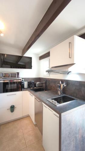 une cuisine avec des armoires blanches et un évier dans l'établissement La Nina - À 5 min de Cassis, à Roquefort-la-Bédoule