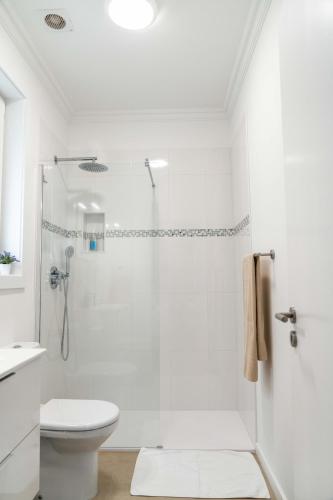 a white bathroom with a shower and a toilet at Incense in Água de Alto