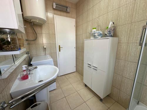 een kleine badkamer met een wastafel en een witte koelkast bij Jovana Apartments in Budva