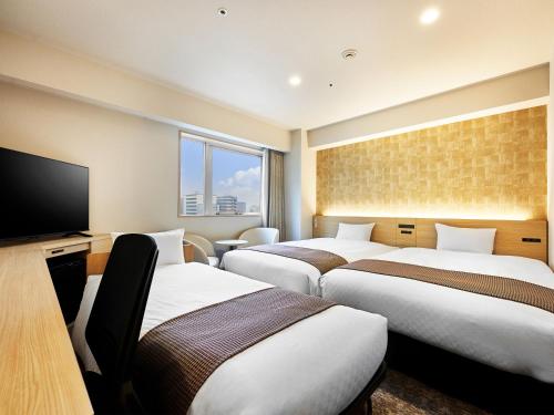 a hotel room with three beds and a flat screen tv at Daiwa Roynet Hotel Gifu in Gifu