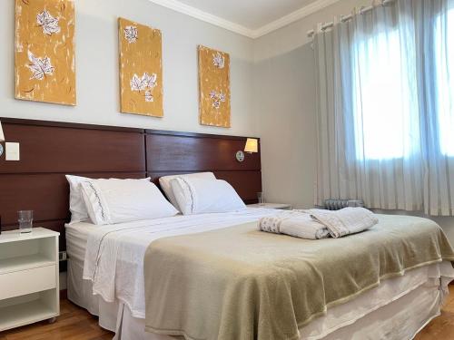 een slaapkamer met een groot bed en een raam bij Cobertura em Campos do Jordão-Capivari in Campos do Jordão