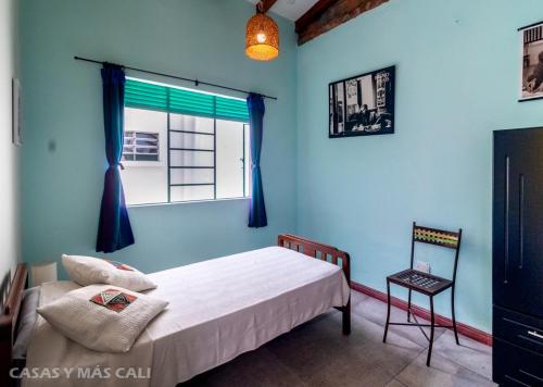 a bedroom with a bed and a window and a chair at Heliconia in Cali