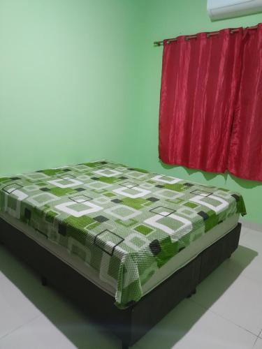 uma cama num quarto ao lado de uma cortina vermelha em CASA RONDÔNIA RURAL SHOW em Ji-Paraná