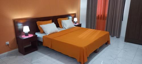 1 dormitorio con 1 cama grande de color naranja y 2 lámparas en Ka-Bela 2 en Sal Rei
