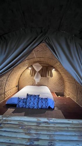 a bed in a tent with two blue pillows on it at Chakerpor bamboo house 3 in Ban Mae Sapok Noi