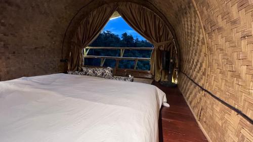 a bedroom with a bed and a large window at Chakerpor bamboo house 3 in Ban Mae Sapok Noi