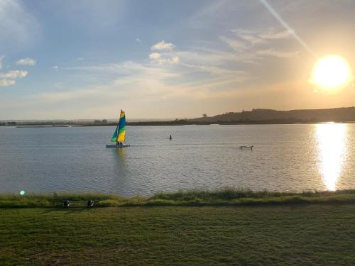 a sail boat in the water at sunset at Pukehina Estuary Sunset Views Townhouse & Studio in Pukehina