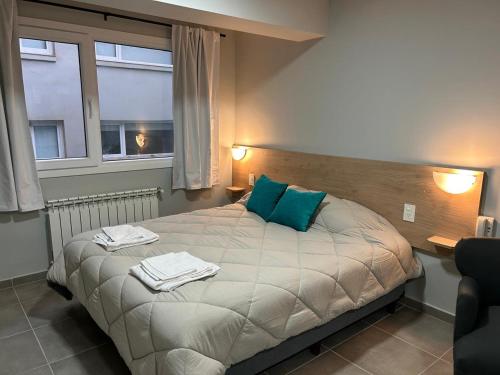 Un dormitorio con una cama con almohadas azules y una ventana. en Monoambiente M670, en San Carlos de Bariloche
