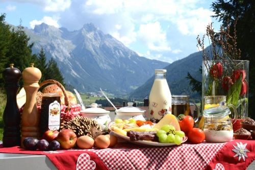 een tafel met groenten en fruit op een rode en witte tafeldoek bij Bacherhof in Sankt Anton am Arlberg