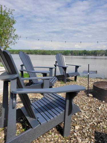 three chairs and a picnic table by the water at Spot Caché - Waterfront - Water sports included! in Papineauville
