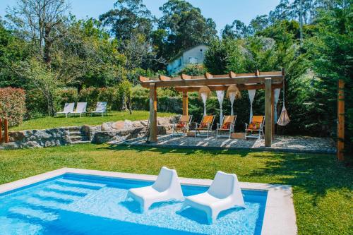 Una piscina con dos sillas blancas y una pérgola. en A Quinta Lanhelas River View, en Caminha