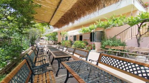 an outdoor patio with benches and tables and plants at Oasis Hostel in Himare