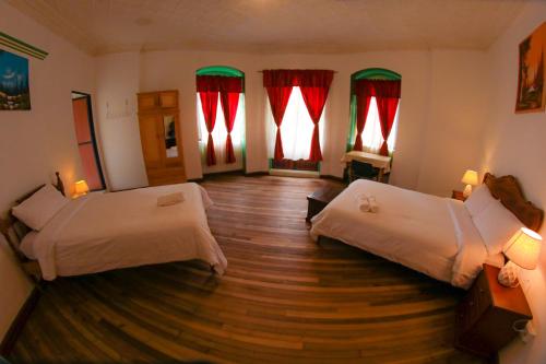 a room with two beds and a wooden floor at Vibes Aurik in Quito