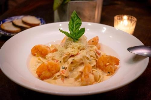 a white plate of pasta with shrimp on a table at Hotel Restaurante Mi Jardin Troncones in Troncones