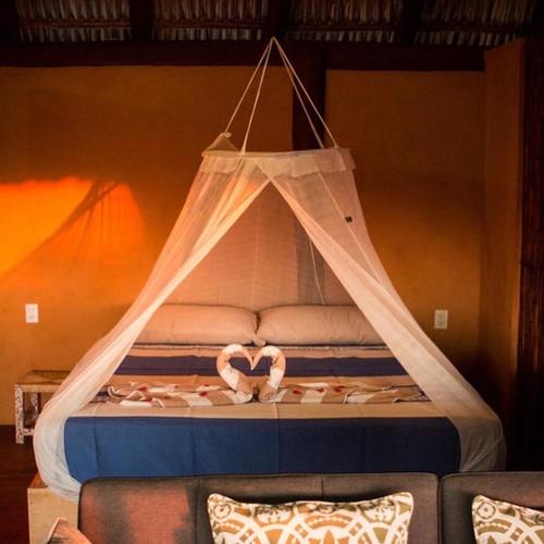a bed with two wedding rings in a tent at Hotel Restaurante Mi Jardin Troncones in Troncones