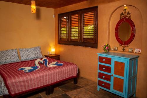 a bedroom with a bed and a mirror and a dresser at Hotel Restaurante Mi Jardin Troncones in Troncones