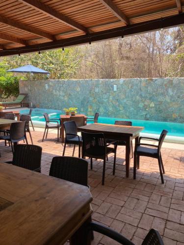a patio with tables and chairs and a pool at Hotel Restaurante Mi Jardin Troncones in Troncones